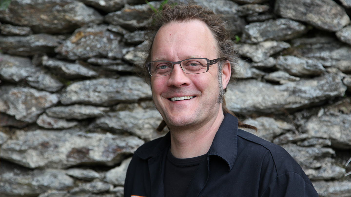 Porträt von Axel Schmitz, Geschäftsführer von firetube, lächelnd vor einer Steinwand.