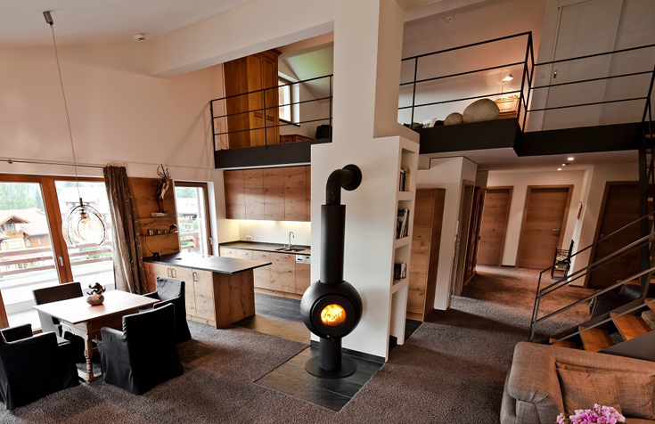 Schwarzer firetube Ofen mit sichtbarem Feuer, freistehend in großem Wohnzimmer.