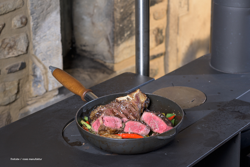 Bratende Pfanne mit Gemüse und Fleisch auf einer Küchenzeile mit Kochplatten.