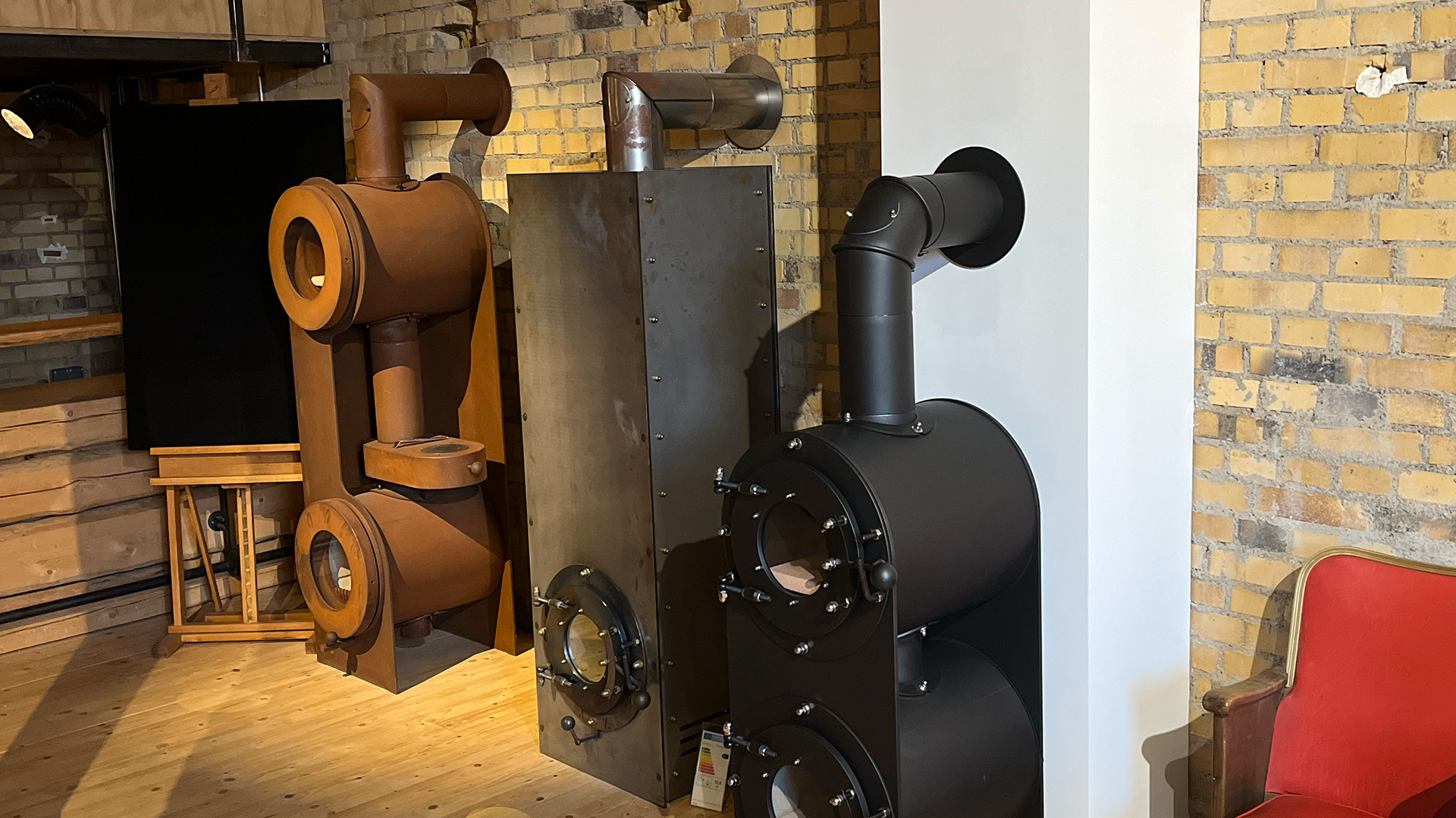 Drei firetube Öfen nebeneinander in unterschiedlichen Designs und Ausführungen, präsentiert in einer Ausstellung.