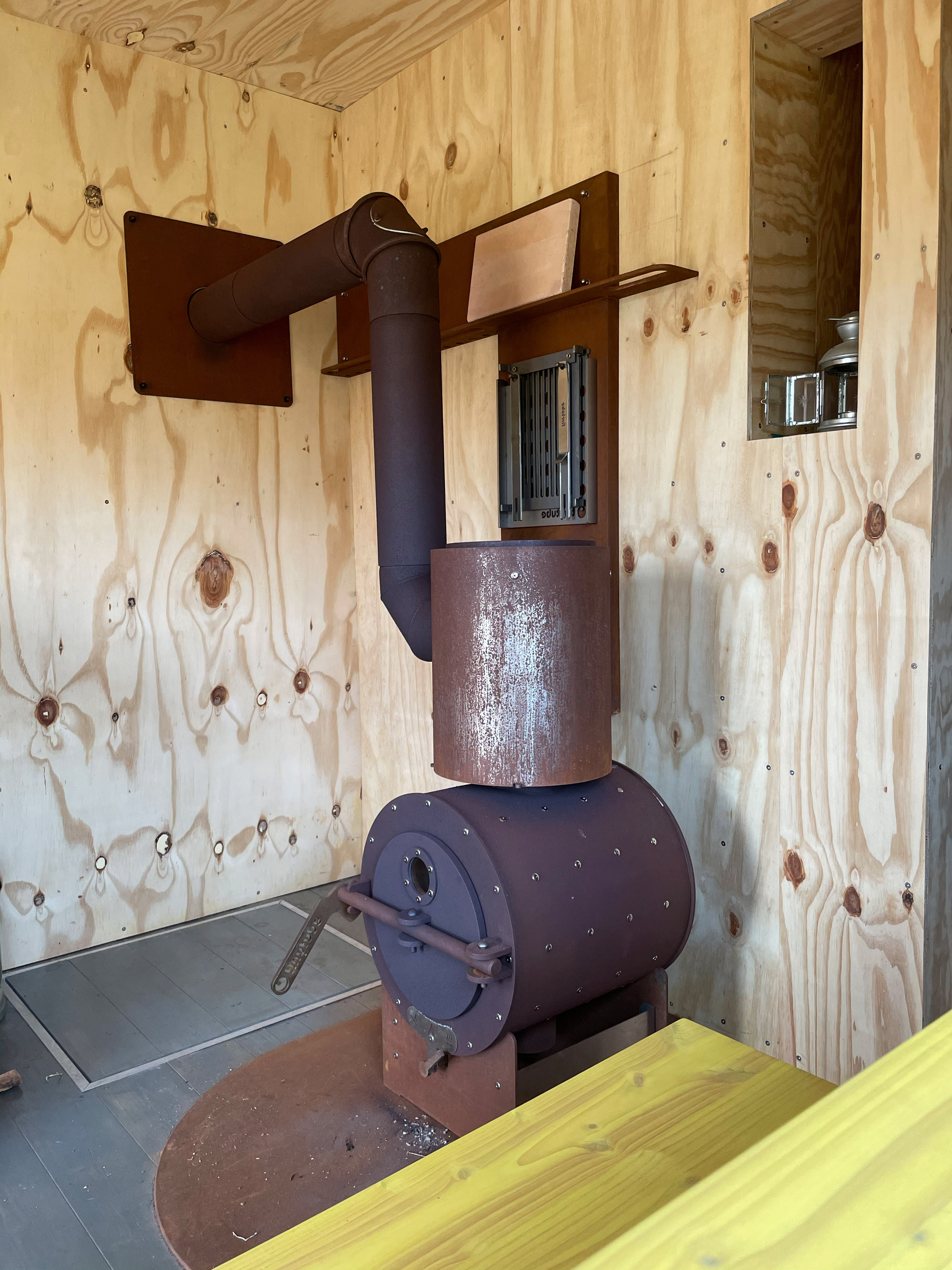 firetube Ofen im rustikalen Stil in einer Raumecke, mit Holzwand im Hintergrund.